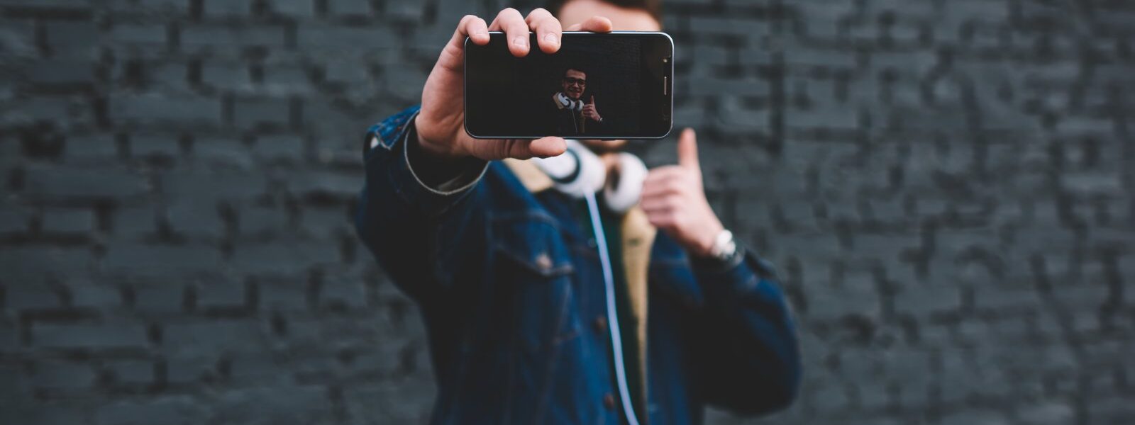 Jak skutecznie wykorzystać marketing influencerów w małych firmach 1 young-man-showing-smartphone-display-beside-brick-2023-11-27-05-02-38-utc