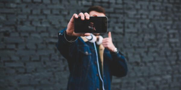 Jak skutecznie wykorzystać marketing influencerów w małych firmach 1 young-man-showing-smartphone-display-beside-brick-2023-11-27-05-02-38-utc